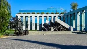 Pomnik upamiętniający ofiary tragicznych wydarzeń historycznych przed nowoczesnym budynkiem w Polsce.